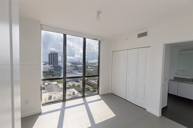 unfurnished bedroom with multiple windows, expansive windows, a closet, and sink