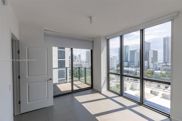 tiled empty room featuring a wealth of natural light and floor to ceiling windows