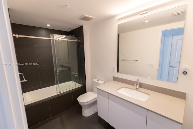 full bathroom featuring tile patterned floors, enclosed tub / shower combo, toilet, and vanity