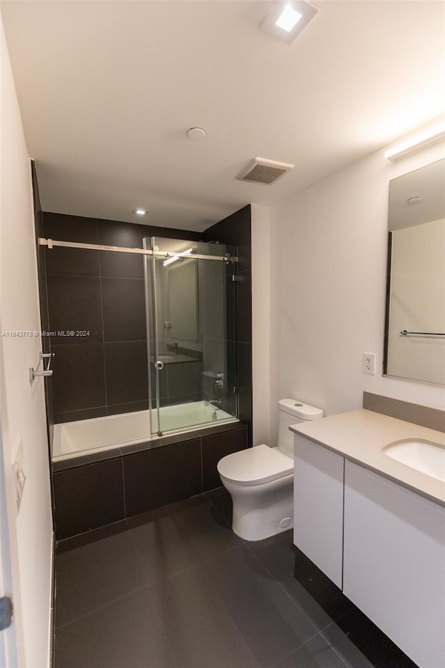 full bathroom with tile patterned floors, toilet, bath / shower combo with glass door, and vanity