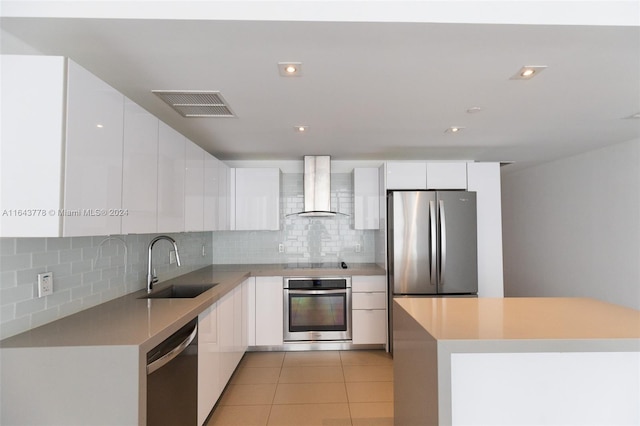 kitchen featuring stainless steel appliances, sink, wall chimney range hood, and white cabinetry