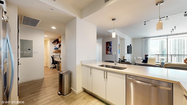 kitchen featuring appliances with stainless steel finishes, white cabinetry, light hardwood / wood-style flooring, decorative light fixtures, and sink