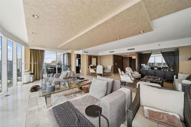 living room featuring a tray ceiling and floor to ceiling windows