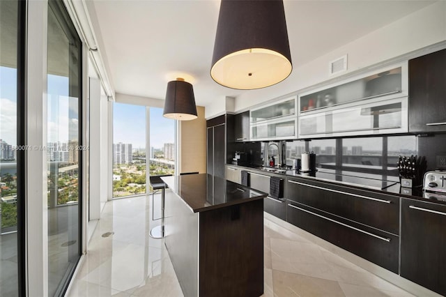 kitchen featuring dark brown cabinets, a center island, floor to ceiling windows, and cooktop