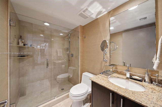 bathroom featuring vanity, toilet, and a shower with door