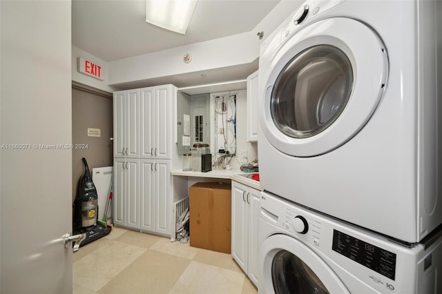 laundry area with stacked washer / dryer and cabinets