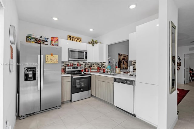 kitchen featuring backsplash, light tile patterned floors, appliances with stainless steel finishes, and white cabinetry