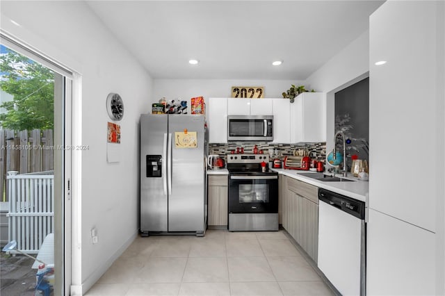 kitchen with backsplash, light tile patterned floors, appliances with stainless steel finishes, white cabinetry, and sink