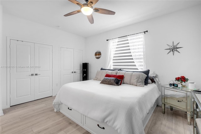 bedroom featuring two closets, ceiling fan, and light hardwood / wood-style flooring