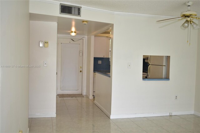 unfurnished room featuring ceiling fan, light tile patterned floors, crown molding, and a textured ceiling