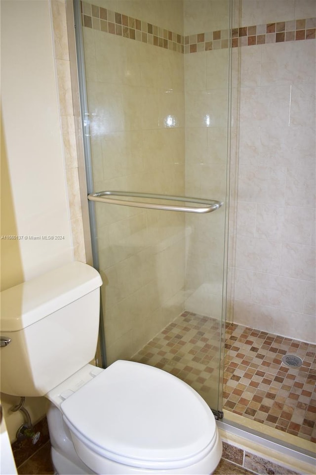 bathroom with toilet, a shower with door, and tile patterned floors