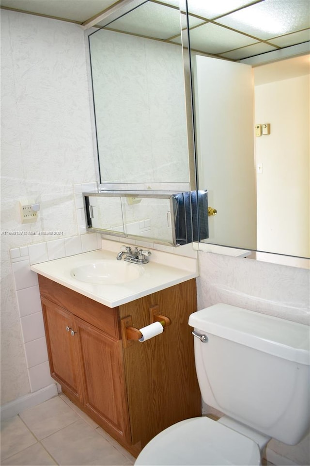 bathroom with tile patterned floors, tile walls, toilet, and vanity