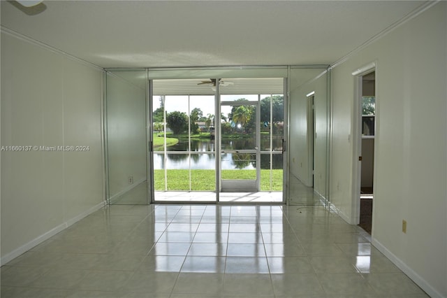 spare room featuring a water view, ceiling fan, light tile patterned floors, and crown molding