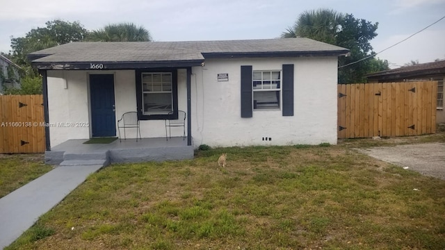 bungalow-style house with stucco siding, roof with shingles, fence, a front yard, and a porch