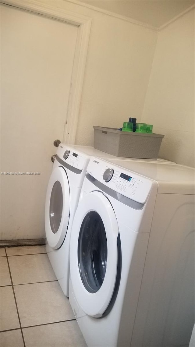 clothes washing area with light tile patterned flooring, laundry area, and washer and dryer
