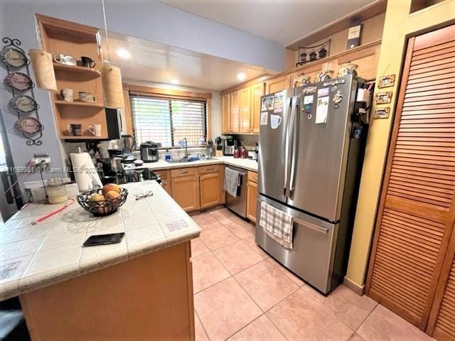 kitchen with light tile patterned floors, stainless steel appliances, sink, light brown cabinets, and kitchen peninsula