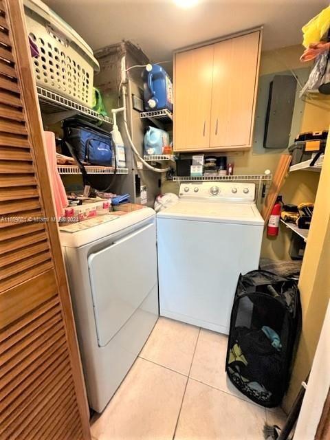 clothes washing area featuring washing machine and clothes dryer, cabinets, and light tile patterned flooring