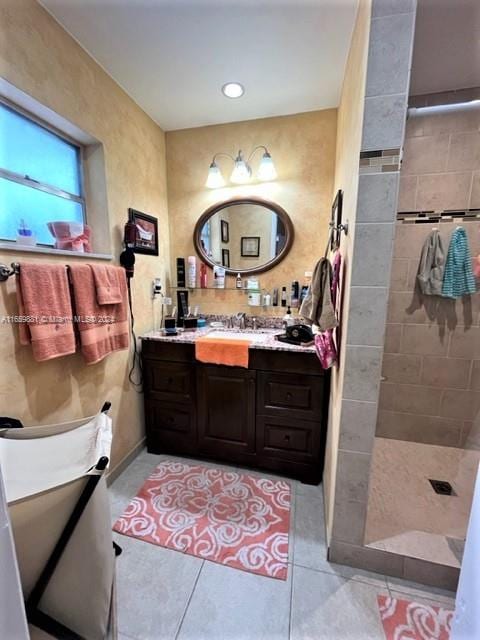 bathroom with tile patterned flooring, a tile shower, and vanity