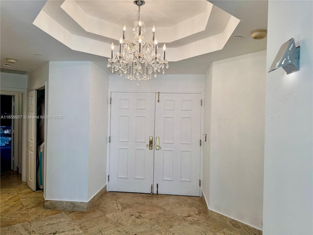 entryway featuring an inviting chandelier and a raised ceiling