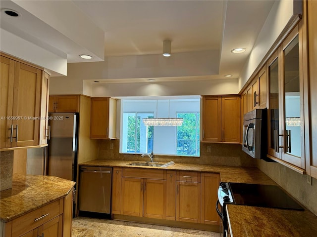 kitchen with stainless steel appliances, light stone counters, tasteful backsplash, and sink