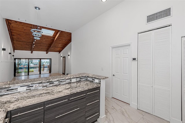 kitchen featuring wooden ceiling, light stone counters, lofted ceiling with skylight, and dark brown cabinetry