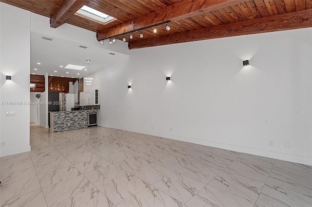 unfurnished living room with wooden ceiling, beamed ceiling, a skylight, and rail lighting