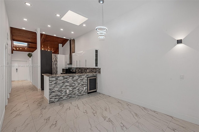 kitchen featuring white cabinetry, a skylight, beverage cooler, exhaust hood, and decorative backsplash