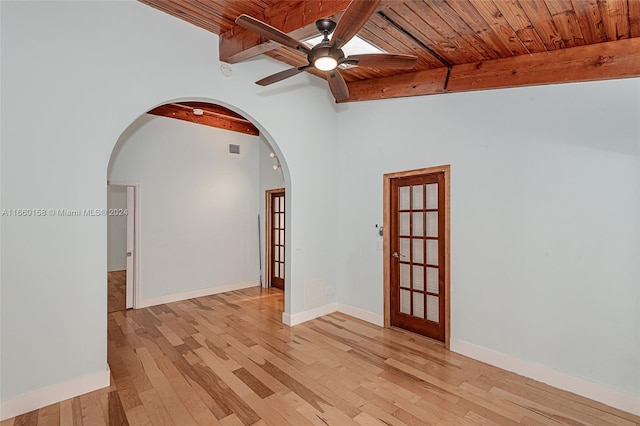 empty room featuring ceiling fan, light hardwood / wood-style floors, vaulted ceiling with beams, and wooden ceiling