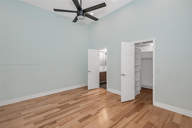 unfurnished bedroom featuring a high ceiling, ceiling fan, a closet, a spacious closet, and light hardwood / wood-style floors