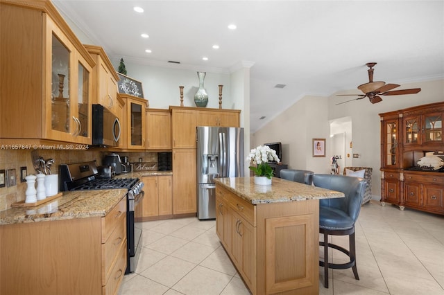 kitchen with appliances with stainless steel finishes, ceiling fan, a kitchen breakfast bar, a kitchen island, and decorative backsplash