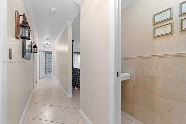 hallway featuring light tile patterned floors, ornamental molding, and a textured ceiling