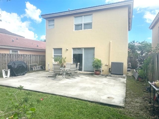 back of house featuring cooling unit, a yard, and a patio