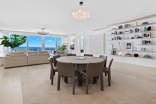 dining room featuring a water view, a chandelier, and light colored carpet