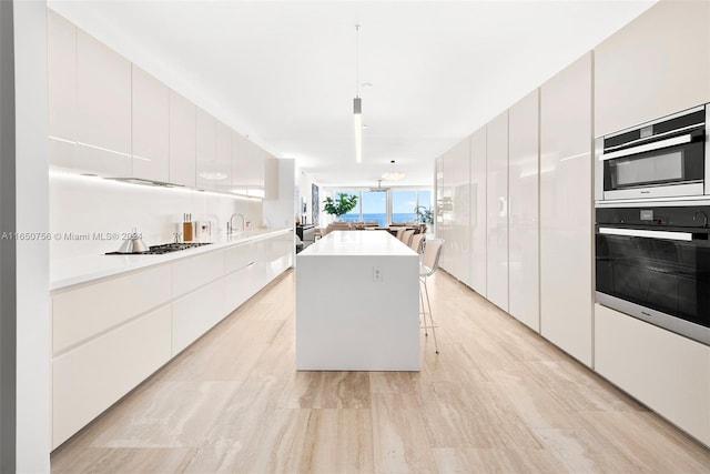 kitchen featuring pendant lighting, a kitchen island, a breakfast bar area, gas stovetop, and white cabinets