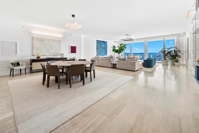 dining space featuring a water view, a wall of windows, and a notable chandelier