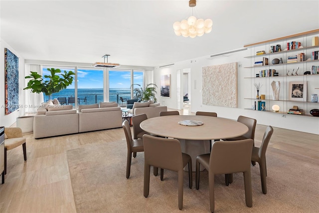 dining area with a water view, light hardwood / wood-style flooring, a wall of windows, and a notable chandelier