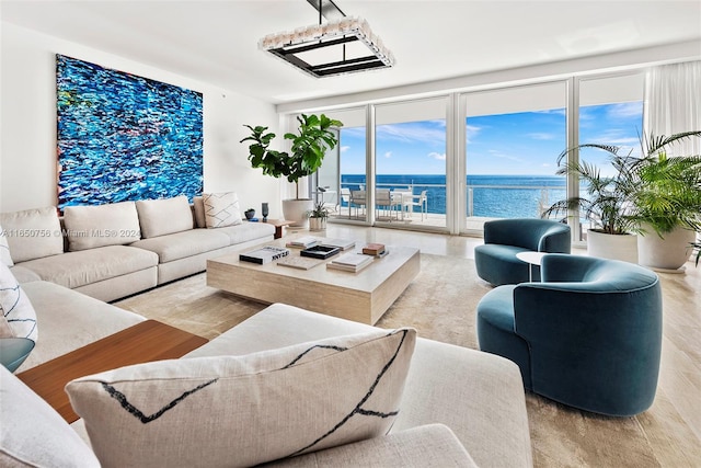 living room featuring expansive windows, light wood-type flooring, and a water view