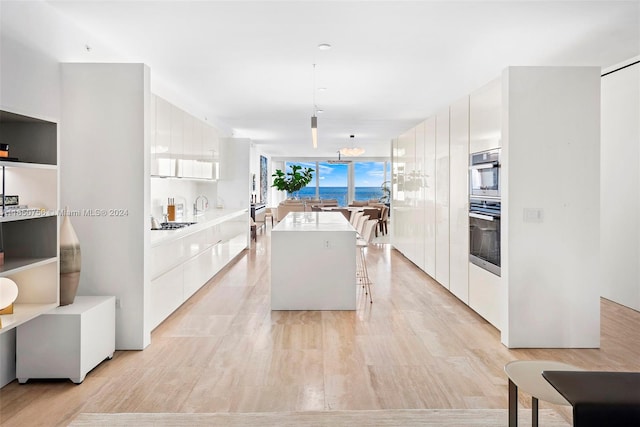 kitchen featuring white cabinets, a kitchen island, light hardwood / wood-style flooring, and decorative light fixtures