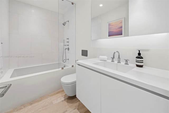 full bathroom featuring wood-type flooring, tiled shower / bath combo, vanity, and toilet