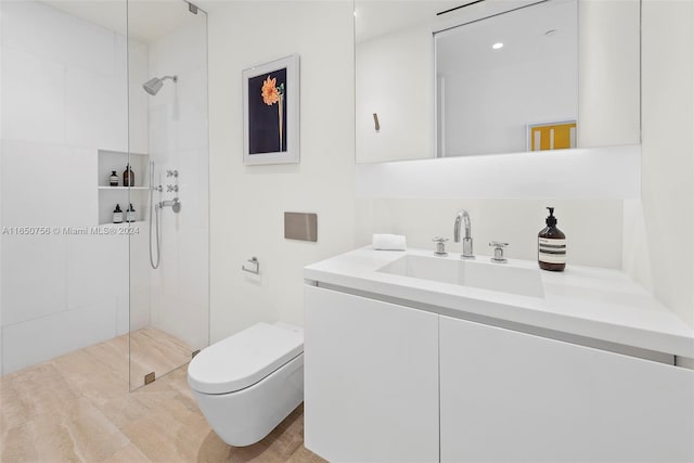 bathroom with vanity, tiled shower, and toilet