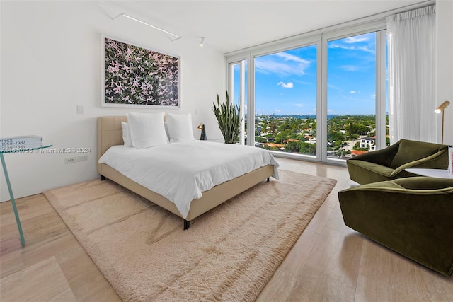 bedroom with access to exterior, expansive windows, and light hardwood / wood-style floors