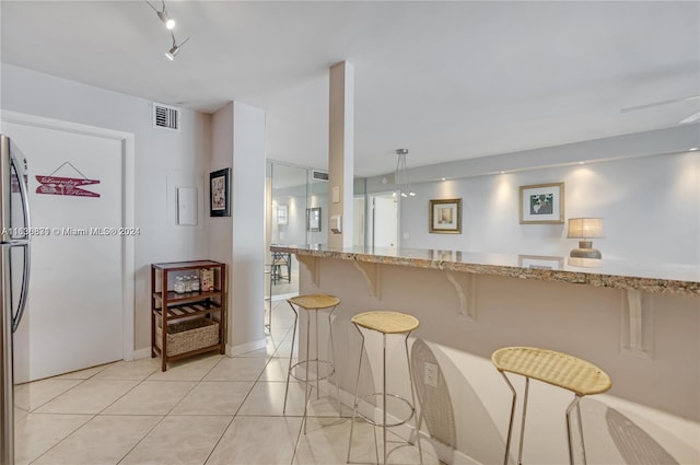 kitchen featuring pendant lighting, light stone counters, a breakfast bar, and light tile patterned floors