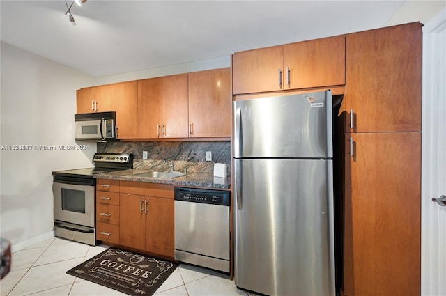 kitchen featuring light tile patterned flooring, stainless steel appliances, tasteful backsplash, and sink