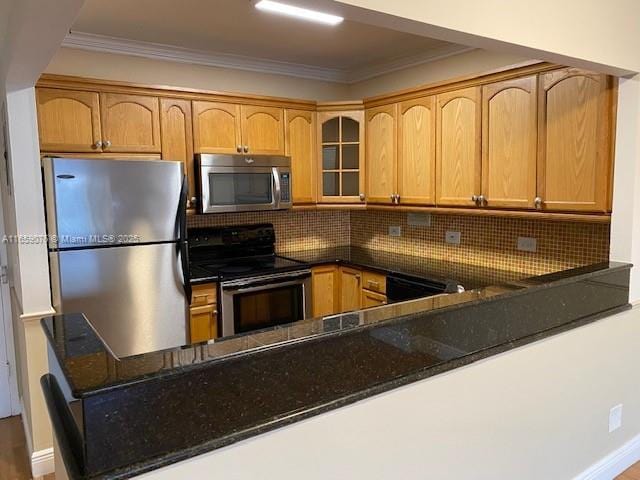 kitchen with crown molding, decorative backsplash, dark stone countertops, kitchen peninsula, and stainless steel appliances