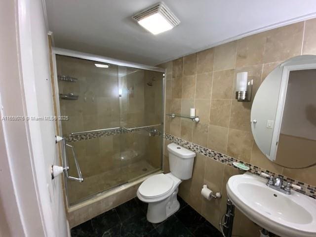 bathroom with tile walls, sink, an enclosed shower, and toilet