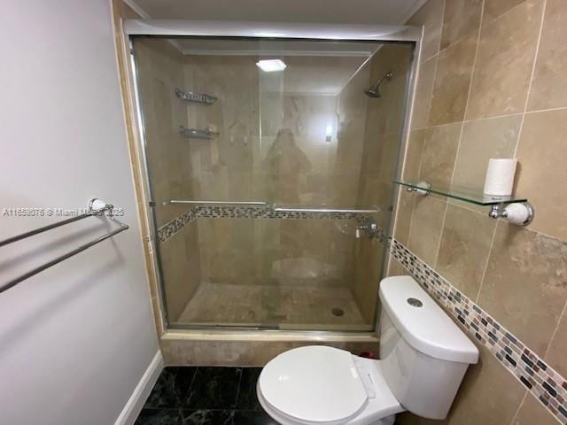 bathroom with tile patterned floors, tile walls, an enclosed shower, and toilet