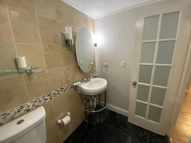 bathroom featuring toilet, tile walls, and sink