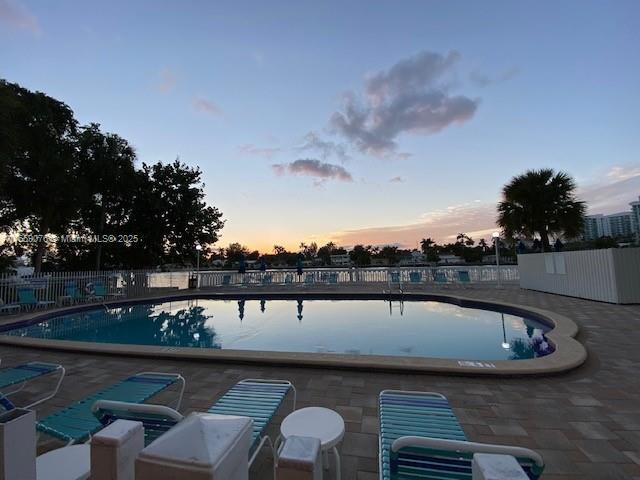 pool at dusk featuring a patio