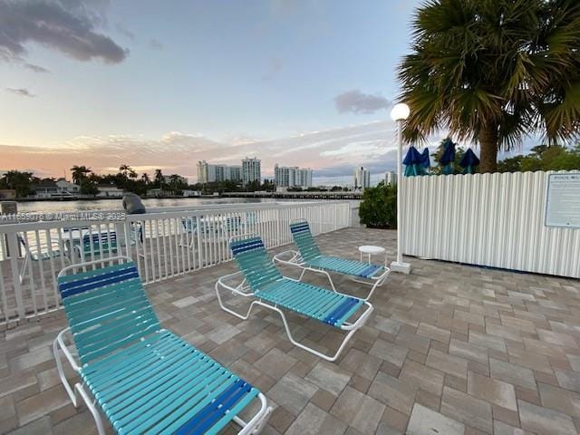 patio terrace at dusk featuring a water view