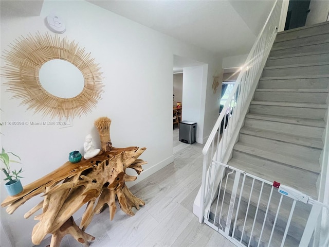 hallway with stairway, baseboards, and light wood-style floors